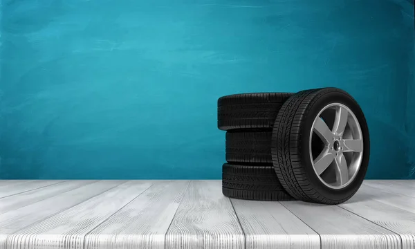 3d rendu d'un seul pneu de voiture appuyé sur trois pneus debout sur une surface en bois devant fond bleu . — Photo