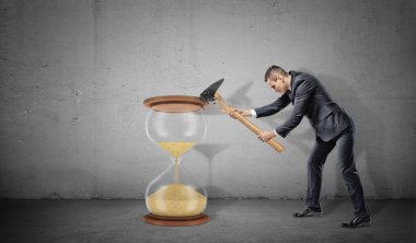 Büyük bir kum saati ama onun çekiç sonları parçalamak için bir işadamı beton arka plan lastikleri.