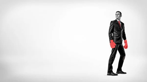 Un uomo d'affari sta a metà turno su uno sfondo mentre indossa un vestito e guanti da boxe rossi . — Foto Stock