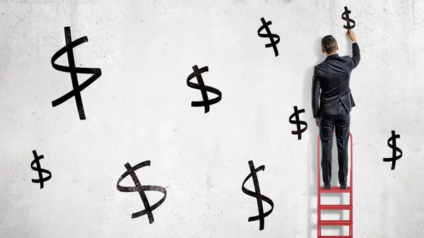 Бізнесмен стоїть на червоній драбині і малює чорні знаки долара на білій стіні . — стокове фото