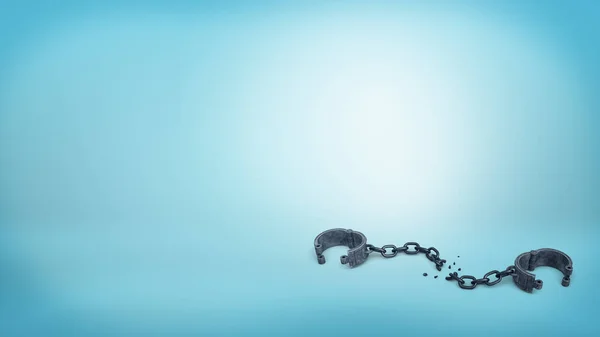 3d rendering of set of iron black handcuffs on a broken chain lying open on a blue background. — Stock Photo, Image