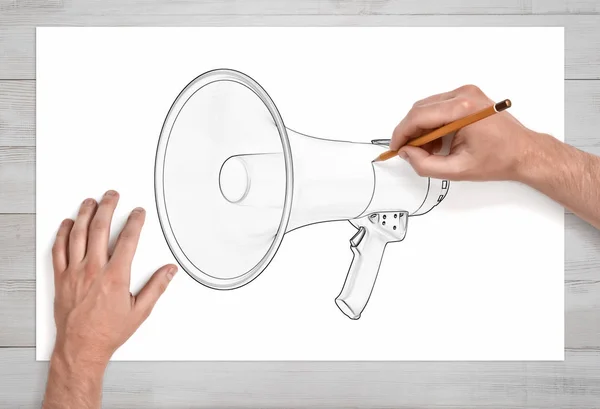 Deux mains masculines en première personne dessinent un mégaphone avec un crayon sur papier blanc . — Photo