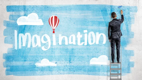 Бизнесмен рисует голубое небо за словом Воображение с воздушным шаром вместо точки над буквой i . — стоковое фото