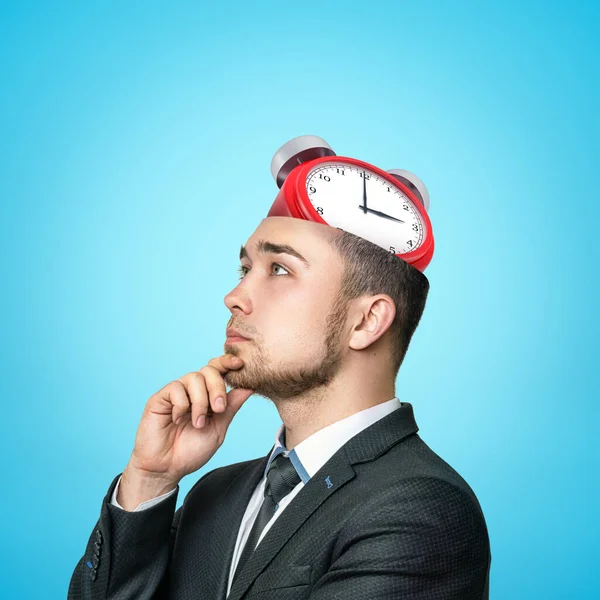 Pensando uomo d'affari con sveglia rossa in testa su sfondo blu — Foto Stock