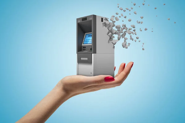 Oldalsó közelkép a nők kéz felfelé néző és a kezében kis ATM, amely kezdett feloldódni darabokra világoskék alapon. — Stock Fotó