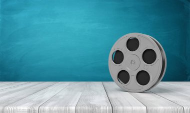 Beyaz ahşap zemin üzerinde film makarası ve koyu turkuaz arka plan