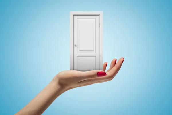 Female hand holding white doorway on blue background — Stock Photo, Image