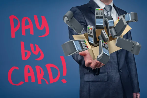 Businessman holding cardboard box filled with PIN pads and Pay by card sign on blue background.