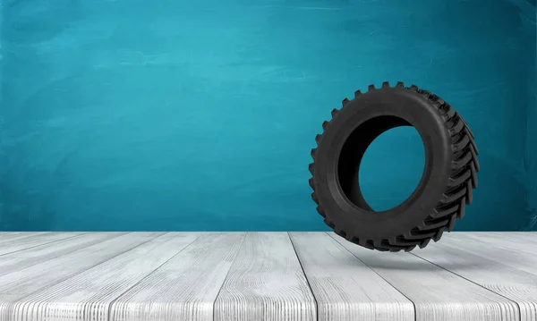 3d rendering van zwarte trekker wiel op witte houten vloer en donker turquoise achtergrond — Stockfoto