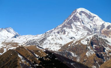 Gürcistan 'daki Gergeti Tapınağı ile dağların arkasında güzel bir manzara.