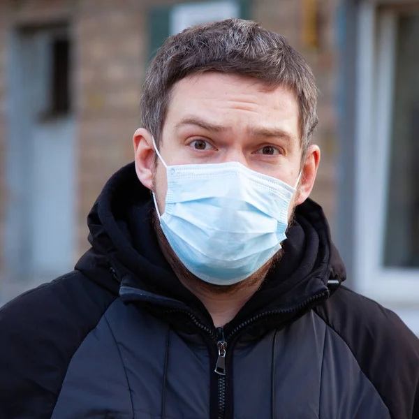 Virus covid-19. A man in a medical mask sneezes and coughs on a street in a city in Europe, protects against coronavirus
