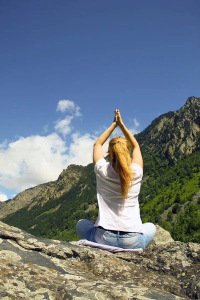 Young woman meditating on top of a mountain in the wilderness — Stock Photo, Image