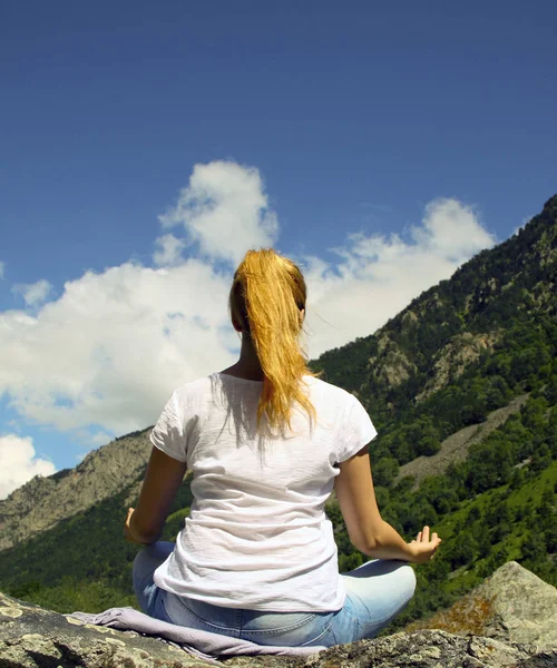 Young woman meditating on top of a mountain in the wilderness — Stock Photo, Image