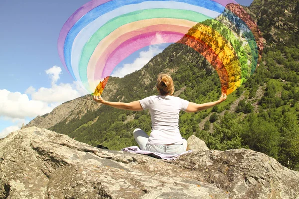 A young girl meditating on a mountaintop with a rainbow in the h — Stock Photo, Image