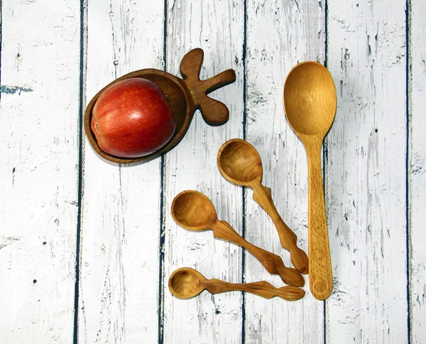 Wooden kitchen spoon and plate with an apple on the table, top v — Stock Photo, Image