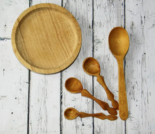Wooden kitchen spoon and plate on the table, top view — Stock Photo, Image
