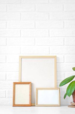 Üç boş ahşap resim çerçevesi ile kopya alanı tablo, boyalı beyaz İskandinav loft tuğla duvar arka plan.
