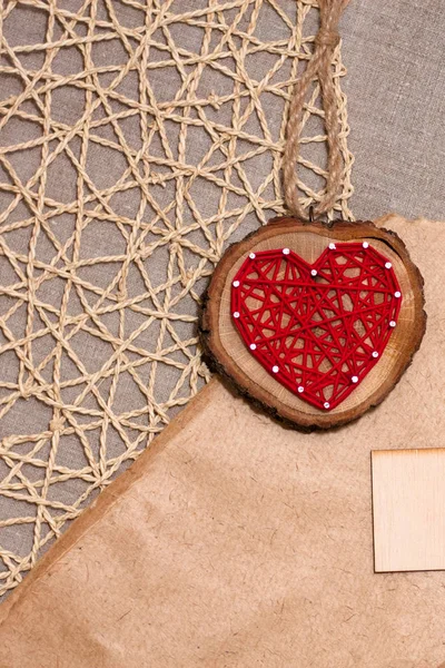 Red heart on a lace natural background on linen textured fabric with a wooden plate with copy space for text.