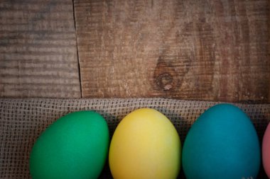Paskalya yumurta keten kumaş üzerinde doğal ahşap dokulu arka plan karşı yay ile renkli. 