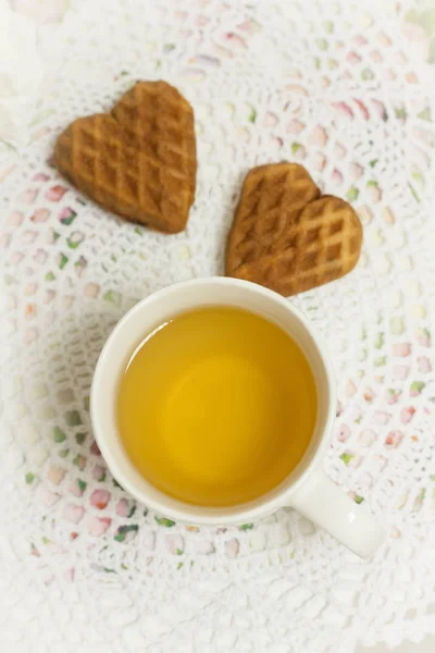 Weiße Tasse Grüntee mit Rosinen, Schokoladenkekse in Shabby Chic, elegantes traditionelles Interieur auf Spitzenserviette mit rosa Blüten. — Stockfoto