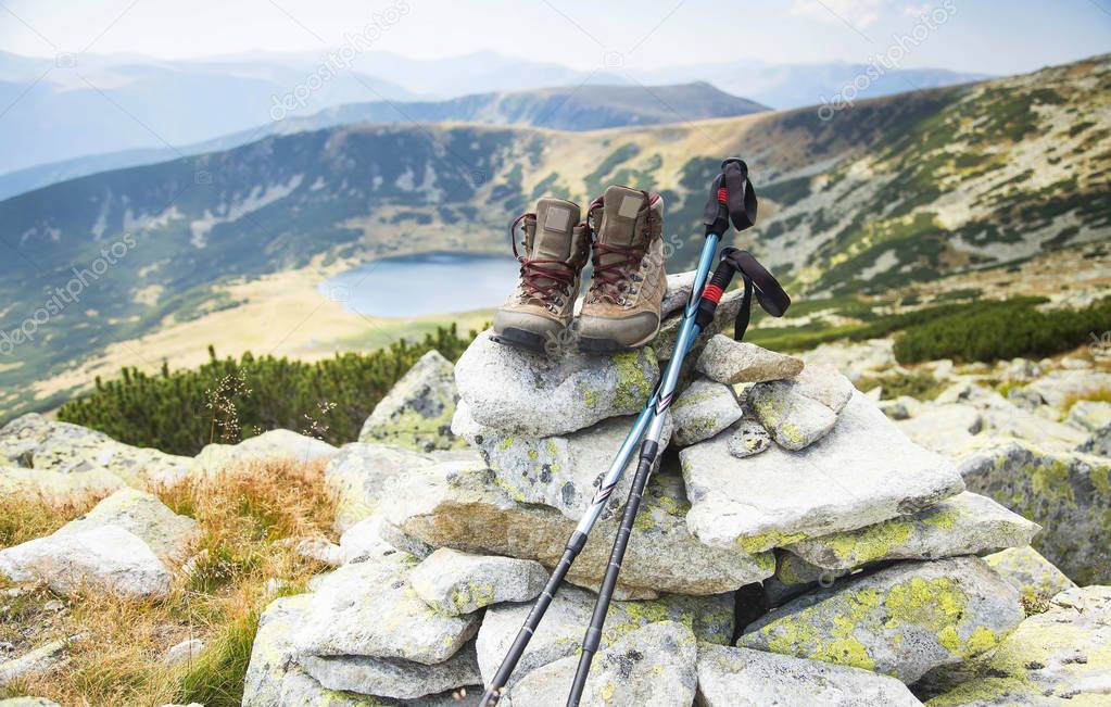 Mountain boots and trekking sticks on mountain peak