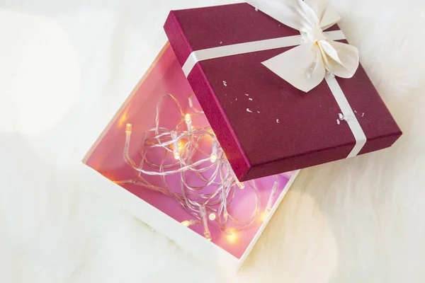 Christmas gift box decorated with tree lights inside — Stock Photo, Image