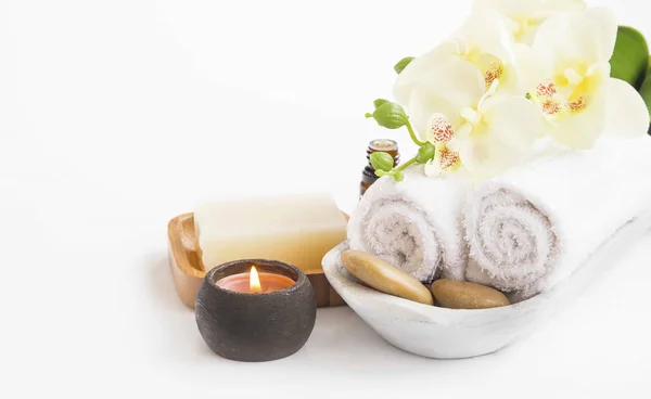 Spa omgeving met orchideebloem, kaars, zeep en handdoeken op whit — Stockfoto