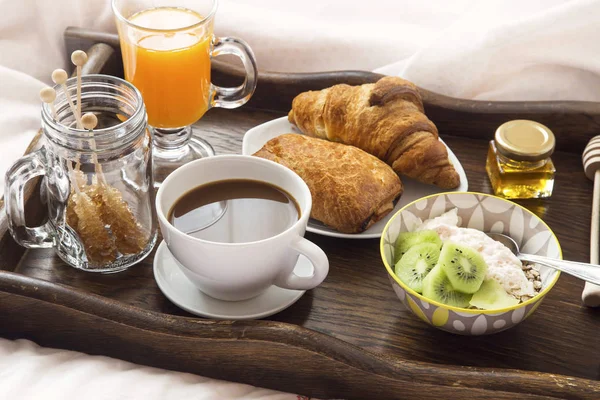 Frühstück im Bett mit Kaffee, Müsli und Joghurt, Orangensaft und — Stockfoto