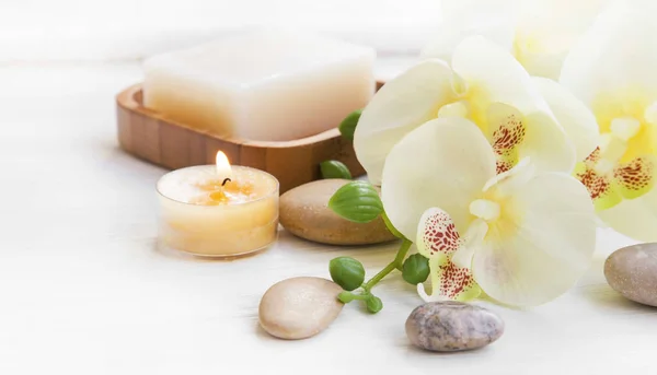 Set de spa con orquídeas, velas y piedras de masaje —  Fotos de Stock