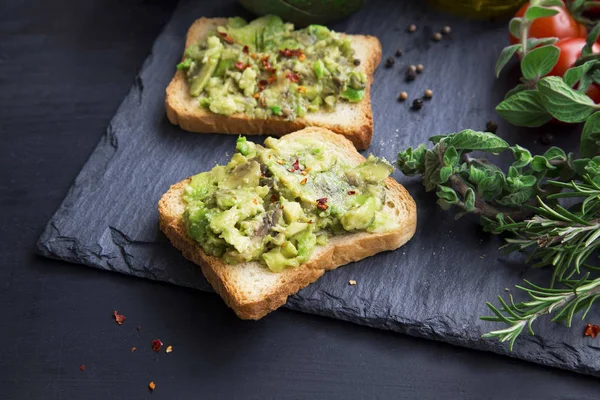 Aguacate en tostadas con copos de chile, hierbas y tomates cherry — Foto de Stock