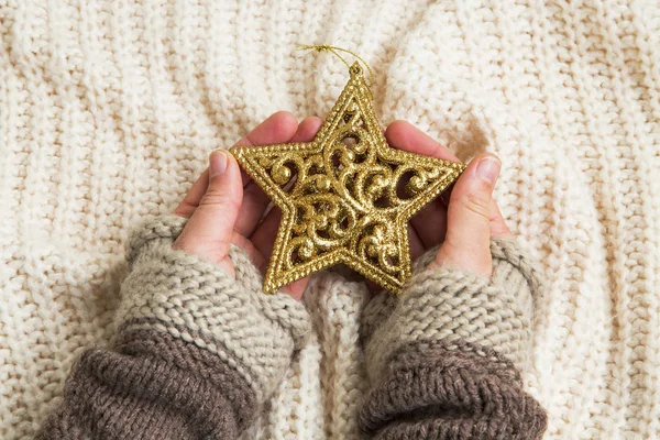 Manos sosteniendo adorno estrella dorada brillo de Navidad — Foto de Stock