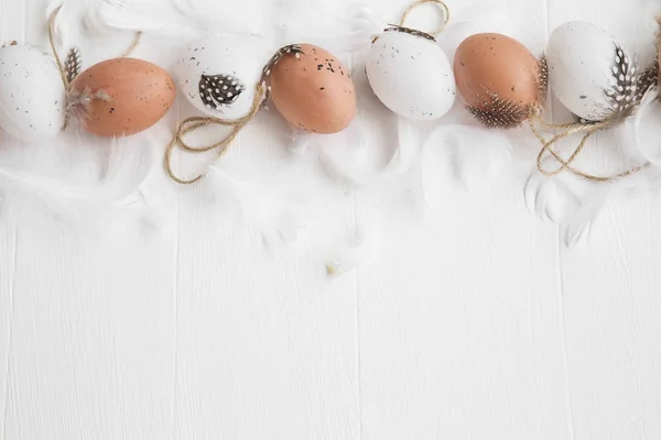Ovos de Páscoa decorados com penas nas costas de madeira pintadas de branco — Fotografia de Stock