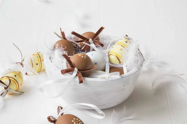 Velikonoční vajíčka zdobená luky a peří v dřevěné misce — Stock fotografie
