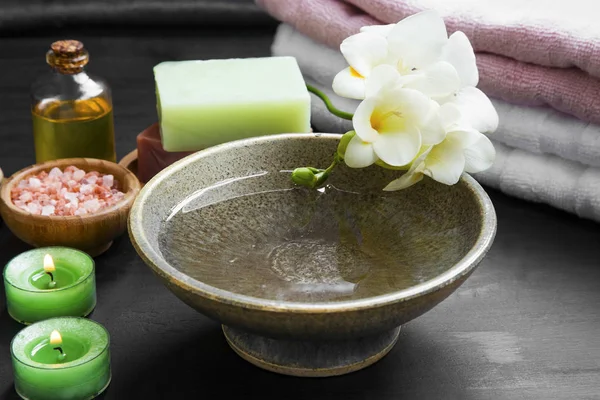 Ambiente de spa relaxante com tigela de água e flores, velas, óleo , — Fotografia de Stock