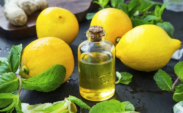 Botella de aceite de limón con bio limones y menta fresca — Foto de Stock