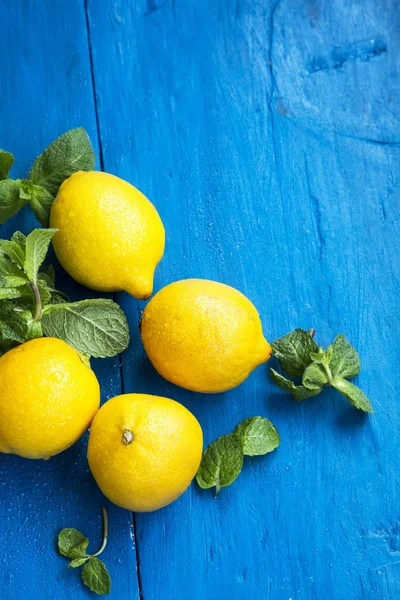 Verse bio citroenen met munt laat kruid op geschilderde houten pagina — Stockfoto