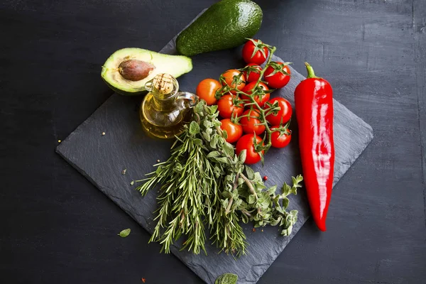 Ervas e produtos hortícolas frescos, especiarias e azeite sobre pedra negra — Fotografia de Stock