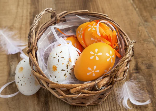 Пасхальные яйца украшены в корзине с перьями на деревянном бэкгре — стоковое фото
