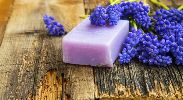Естественное мыло ручной работы с фиолетовыми цветами на деревянном фоне — стоковое фото