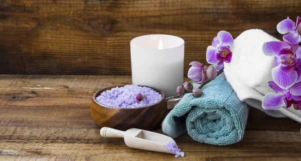 Spa still life with towels, salt and orchid on wooden background — Stock Photo, Image