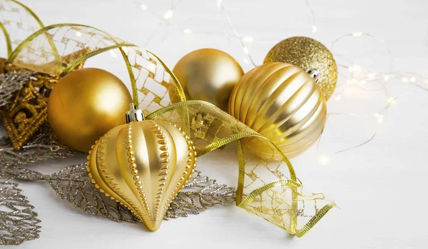 Золотые рождественские украшения с мячами, лентами и огнями — стоковое фото