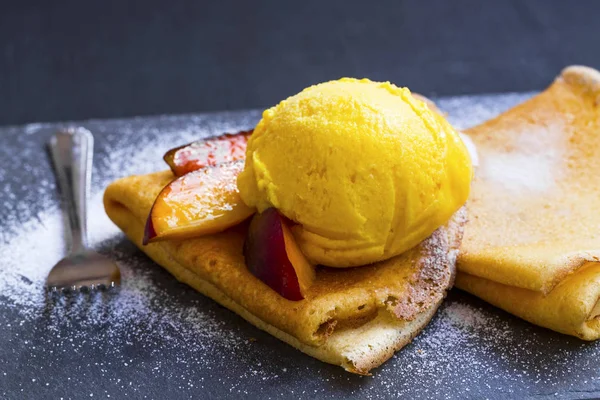 Crêpes farcies à la confiture, tranches de pêche et cuillère à crème glacée sur le dessus — Photo