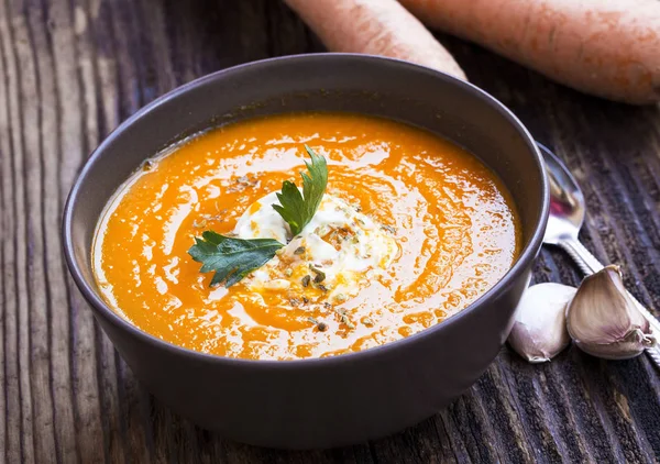 Creamy carrot soup with cream sauce on top, rustic vegetable sou