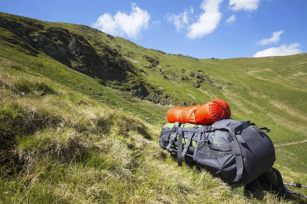 Bergwanderrucksack Ausrüstung auf dem Gras mit Berg la — Stockfoto