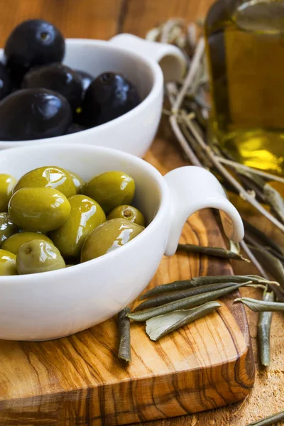 Olive verdi e nere in olio su tavola rustica di legno. Ital — Foto Stock