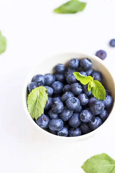 Blueberries fruits closeup in a bowl with green mint leaves — Stock Photo, Image