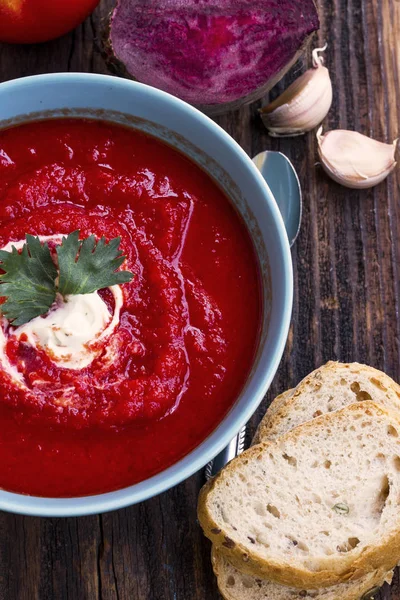 Tomatoes and beetroot rustic soup bowl on wooden board — Stock Photo, Image