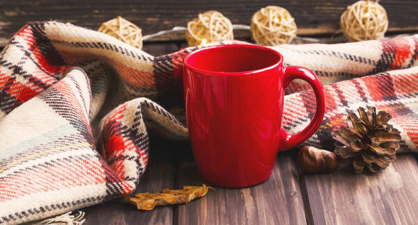 Cozy autumn blanket and tea cup , fall setting on wooden backgro