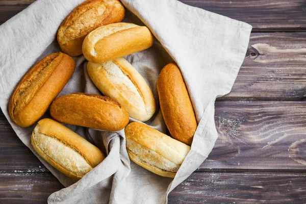 Fresh bread buns in a towel on wooden board — Stock Photo, Image