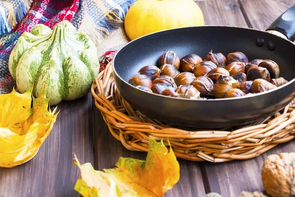 Castanhas assadas em uma panela com abóboras de outono e bordo seco — Fotografia de Stock